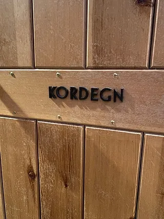 billede af trædør med sort skilt hvor der står "kordegn"